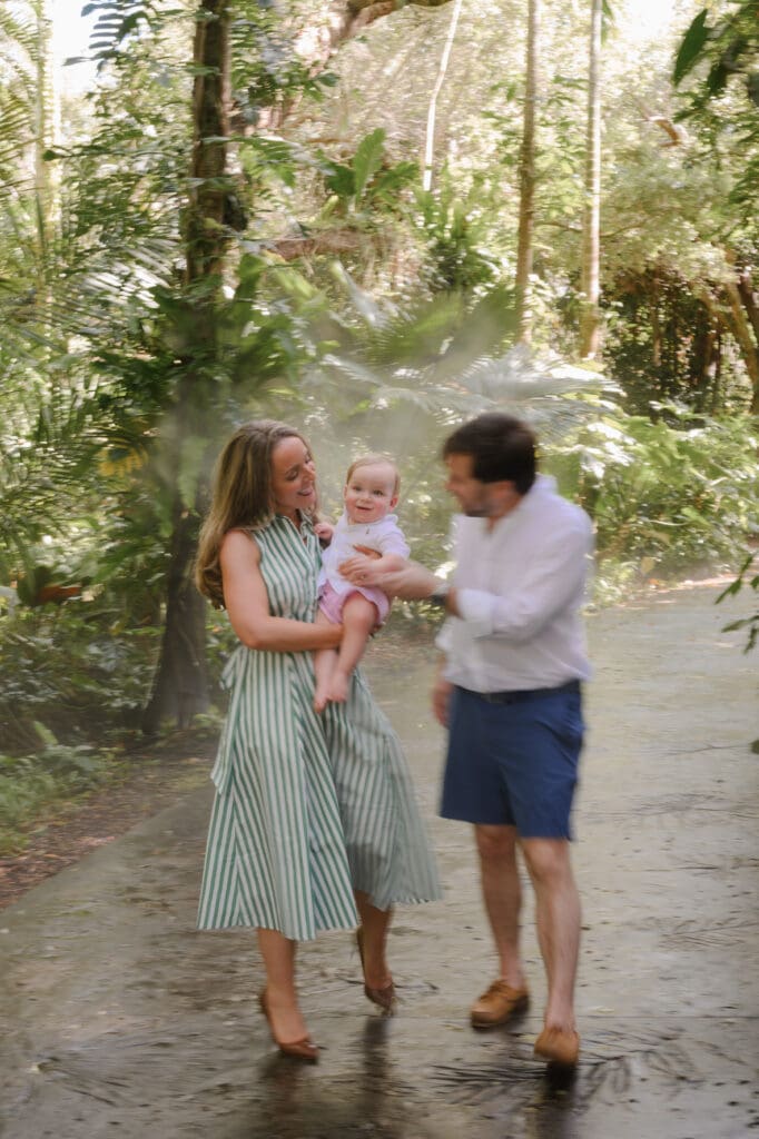 Family photography session at Fairchild Tropical Botanic Garden in Miami, walking through lush tropical greenery with their baby