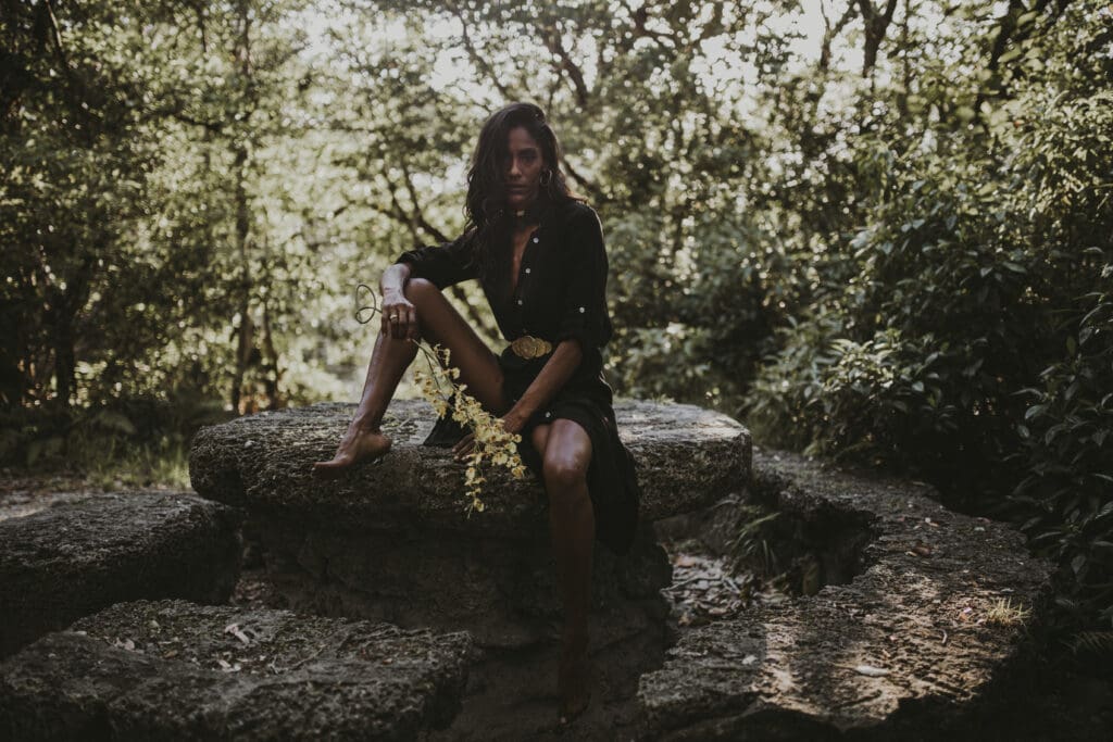 Portrait photography at Greynolds Park in North Miami Beach, woman sitting barefoot on historic stone structure surrounded by oak hammocks and lush greenery
