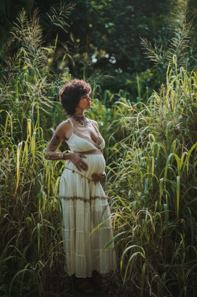 Maternity photography at Earth ’n Us Farm in Little Haiti, pregnant woman in bohemian dress surrounded by tall grass and tropical greenery