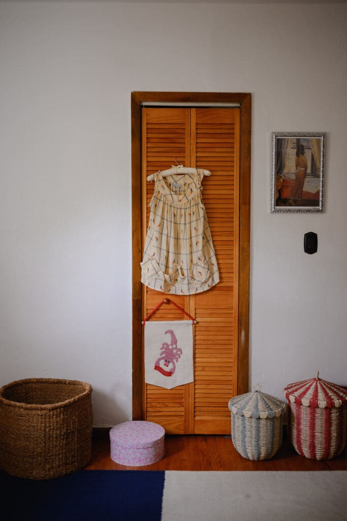 Sentimental maternity dress hanging on a wooden closet door with family keepsakes in a home
