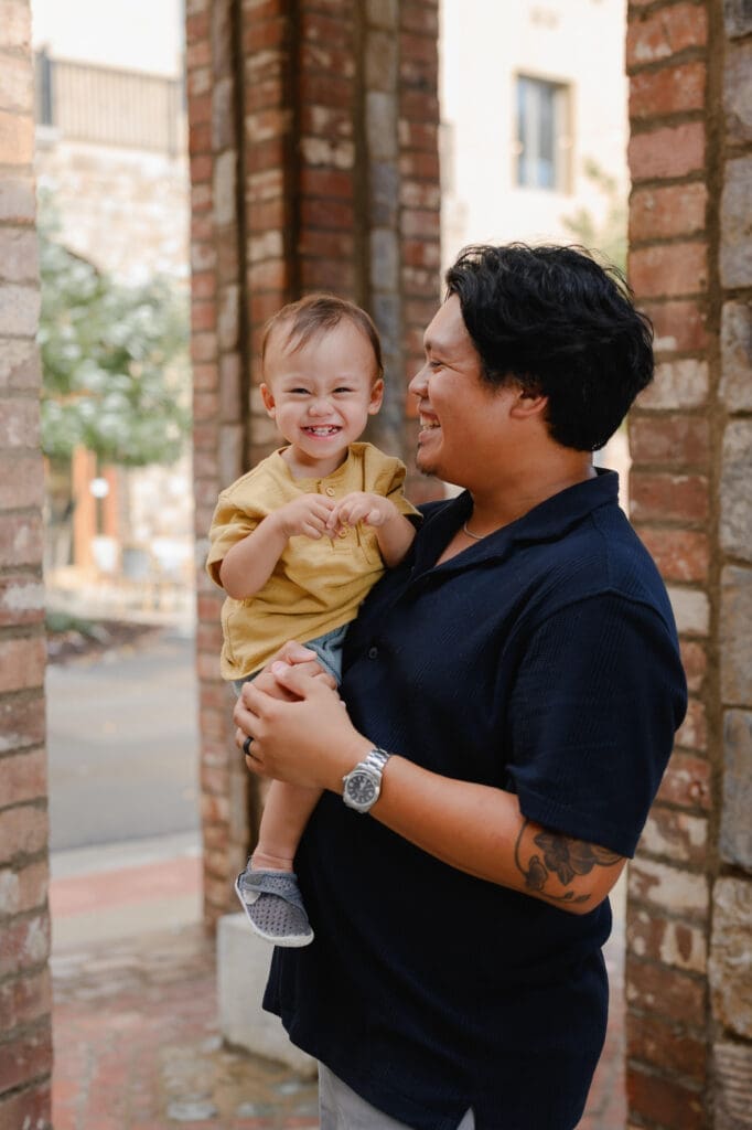 Father holding his smiling toddler during a family photography session at BridgeWay Station in Greenville, South Carolina.