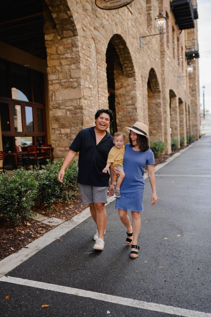 Family walking together beneath the stone archways at BridgeWay Station during a lifestyle family photo session in Greenville, South Carolina.